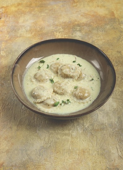 Ravioli in cream sauce, spices and herbs, top view, no people