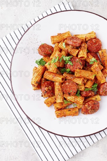 Rigatoni pasta with spicy sausage, and rich tomato sauce served, on a white plate, homemade