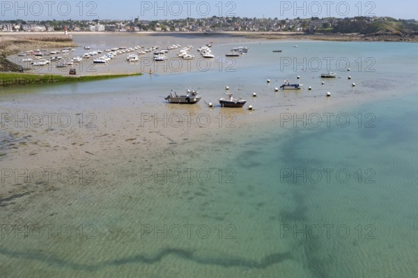 View of shallow turquoise water and moist sandy soil at low tide (low tide), with shadows of currents and rocks visible in the water and numerous small boats drying in the background, Erquy, Saint-Brieuc Bay, Côtes-d'Armor Department, Brittany Region, France
