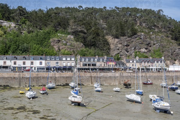View of Erquy Bay at low tide with a fortified promenade behind which a series of bright, multi-storey residential buildings extend along Rue du Port, Erquy, Saint-Brieuc Bay, Côtes-d'Armor, Brittany region, France