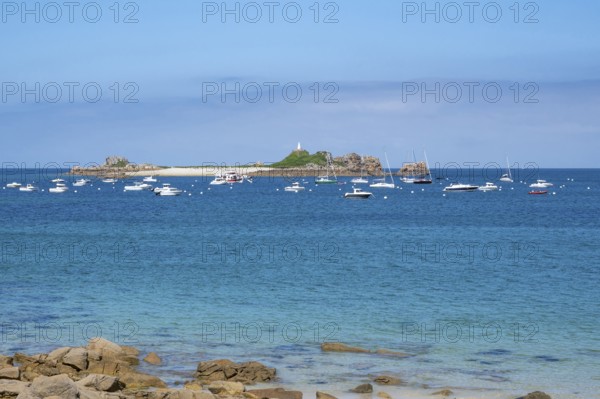In the turquoise-blue waters of the English Channel, motor boats and sailboats anchor off small, rocky islands Sport Blanc, Penvenan, Cotes-d'Armor, Brittany region, France
