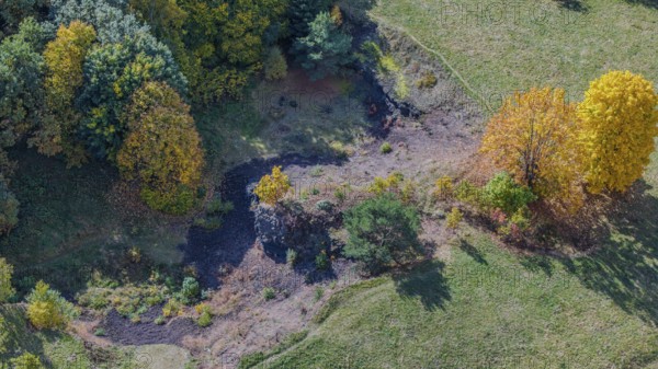 A picturesque view of a hilly landscape in autumn, with colorful deciduous trees, a small clearing and gentle elevations. The colors of the leaves shine in the sun. Železná hurka, Czech Republic