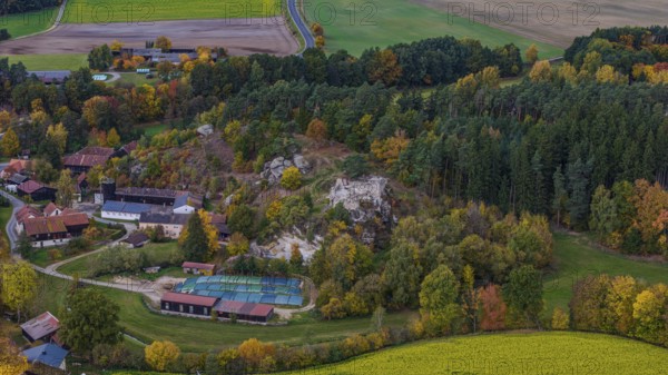 A picturesque village is surrounded by colorful trees in autumn. A castle ruin is nearby, while the fields are glowing green. Clear view of the region's natural beauty. Liebenstein, Upper Palatinate
