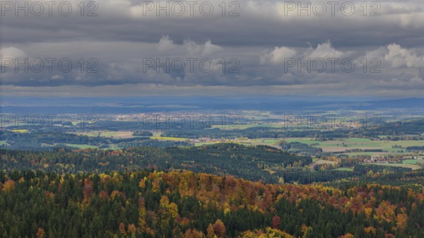 The scene shows an autumnal landscape with colorful trees and rolling hills under a cloudy sky. The view extends far over the valley and the fields. Altglashütte, Upper Palatinate
