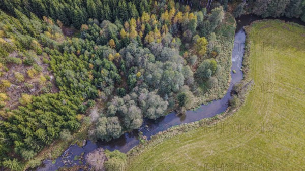 The river snakes through the countryside, surrounded by green trees and golden yellow leaves. The vast fields offer a peaceful view on a sunny day. Falkenberg, Upper Palatinate