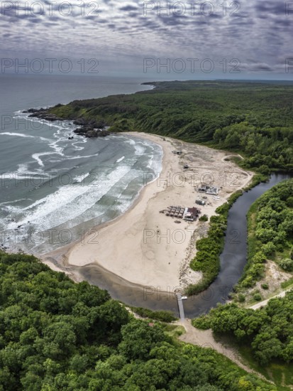 A sandy beach with a river flowing into the sea surrounded by forests. Aerial view to beautiful Silistar beach near to Sinemorec, Burgas, Bulgaria