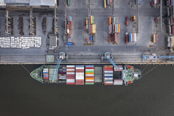 Aerial view of a cargo ship docked at a port with colorful containers and industrial surroundings. Aerial view of container ship on port of Burgas, Bulgaria. Logistics and transport