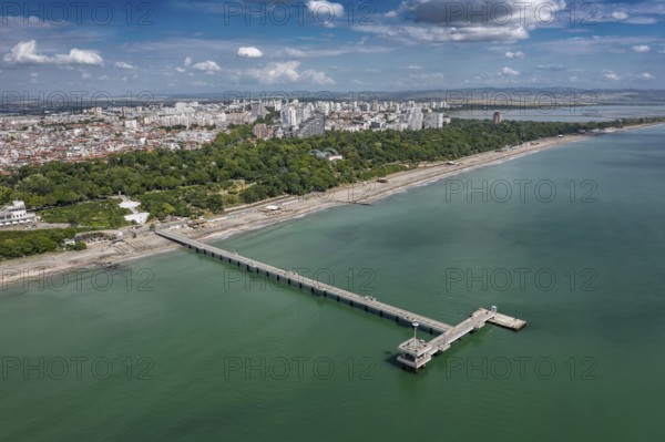 Aerial view of a long pier extending into the sea with cityscape in the background. Aerial view to bridge in the sea in Burgas, Bulgaria
