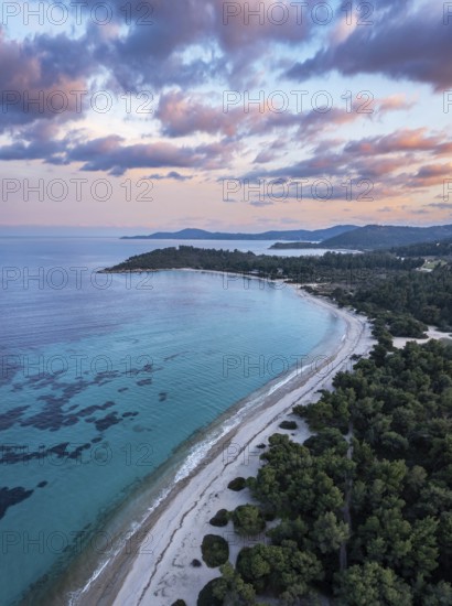Aerial view of a beach and coastal forest with a peaceful sea at sunset. Aerial view of Glarokavos beach in Kassandra peninsula. Chalkidiki, Greece