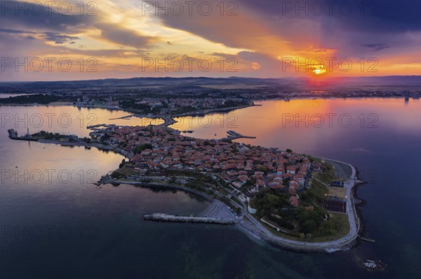 Aerial view of a peninsula at sunset with an orange sky and calm sea. Aerial view to old town of Nessebar, Bulgaria at sunset