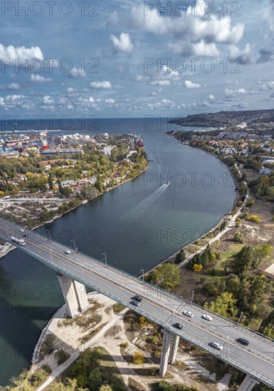 Aerial view of a bridge with cars spanning a winding river within an urban landscape. Aerial view of big bridge with cars above lake towards Varna, Bulgaria