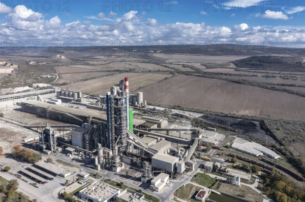 Aerial view of a sprawling industrial complex with rural fields in the background. Aerial view to cement plant near to Devnya, Varna, Bulgaria. Devnya cement plant