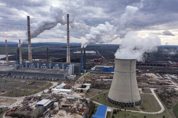 Aerial view of a power plant with multiple smokestacks releasing smoke under a cloudy sky. Aerial view of thermal power plant Maritsa East 2 Stara Zagora Region, Bulgaria