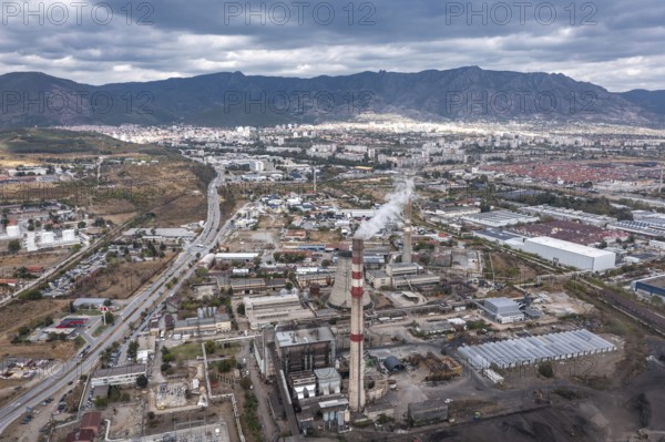 City with industrial facilities and smokestacks nestled among nearby mountains. Aerial view of thermal power station in Sliven, Bulgaria