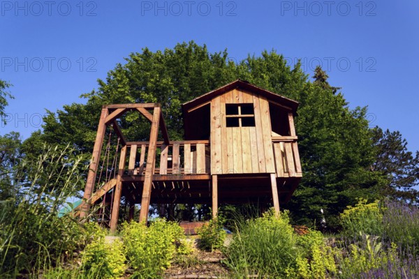 Beautiful wooden children playhouse with swing and slide on hillside Krivoklat Czech republic