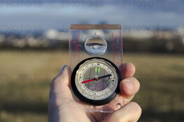 Male hand holding glass compass, nature in background, sunny autumn day, life change and new years resolutions concept Prague Czech republic