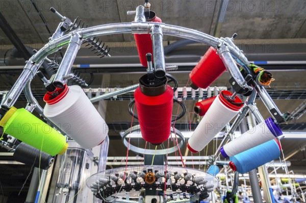 Colorful reel thread set up at modern and automatic sewing or embroidery spinning machine, textile industry factory concept Prague Czech republic