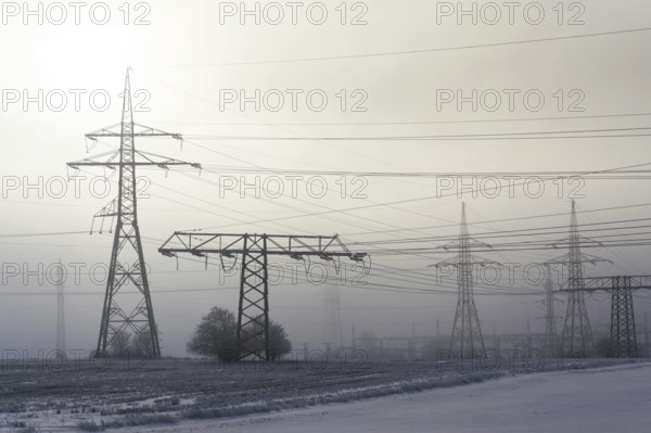Electricity pylons from distribution power station in foggy winter freeze Prague Czech republic