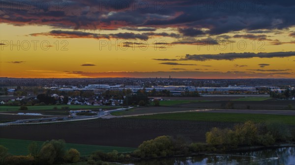 At sunset, the city of Straubing is painted in warm colors. The Danube flows calmly, while the clouds in the sky turn orange and pink and the landscape is illuminated. Straubing, Lower Bavaria