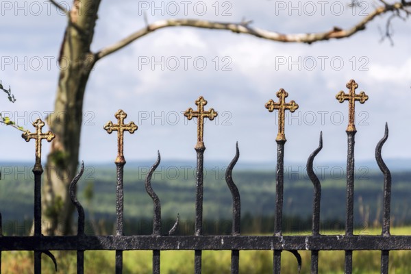 Beautiful small iron crossed fence decoration, graveyard wall with green woods in background, life and death concept Prague, Czech republic