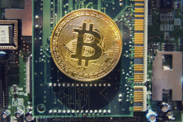 Golden bitcoin coin lying on computer motherboard, cryptocurrency mining concept Prague Czech republic