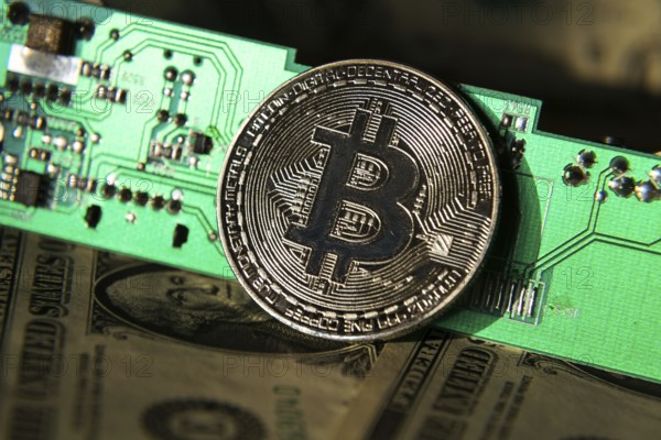 Silver bitcoin coin with dollars and computer motherboard, cryptocurrency mining concept Prague Czech republic