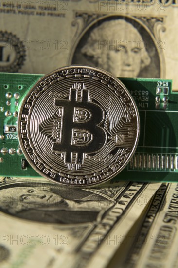 Silver bitcoin coin with dollars and computer motherboard, cryptocurrency mining and investing concept Prague Czech republic