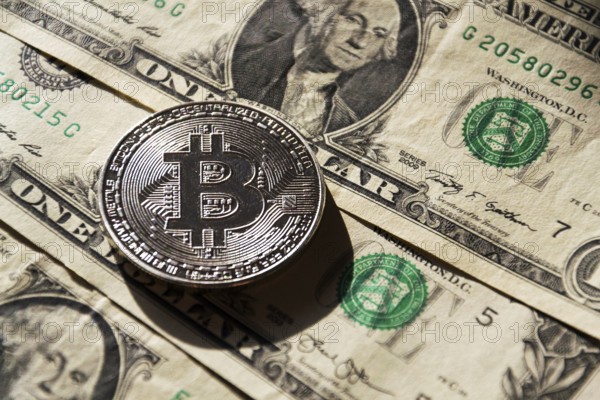 Silver bitcoin coin lying on United States dollars, cryptocurrency concept Prague Czech republic