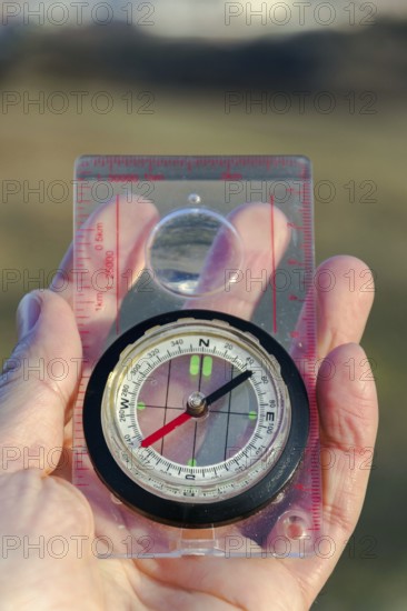 Male hand holding glass compass, nature in background, sunny autumn day, life change and new years resolutions conceptMale hand holding glass compass, nature in background, sunny autumn day, life change and new years resolutions concept Prague Czech republic