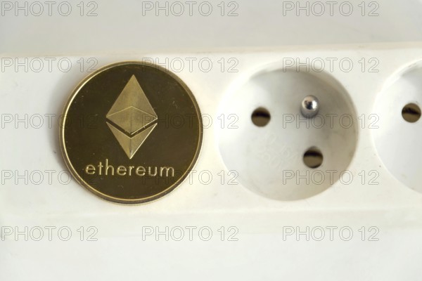 Ethereum coin lying on power strip extension cord with empty socket, cryptocurrency energy consumption and footprint concept, isolated on white background Prague Czech republic