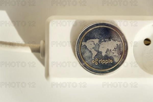 Ripple coin lying on power strip extension cord with empty socket, cryptocurrency investing, energy consumption and footprint concept, isolated on white background Prague Czech republic