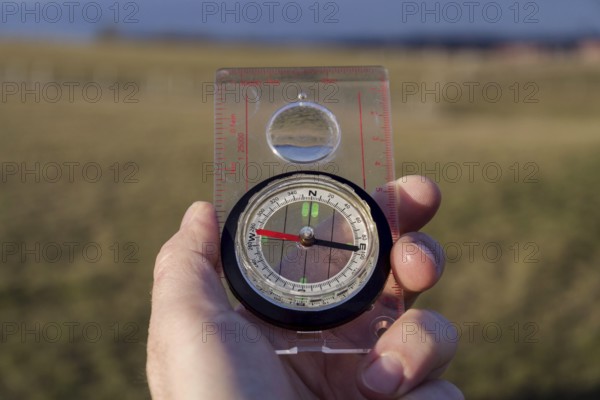 Male hand holding glass compass, nature in background, sunny autumn day, life change and new years resolutions conceptMale hand holding glass compass, nature in background, sunny autumn day, life change and new years resolutions concept Prague Czech republic