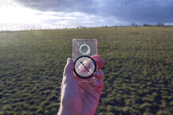 Male hand holding glass compass, nature in background, sunny autumn day, life change and new years resolutions concept Prague Czech republic