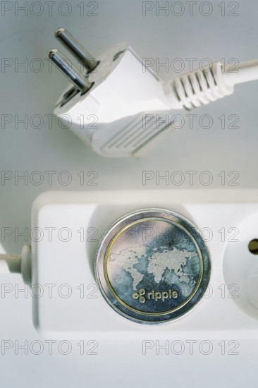 Ripple coin lying on power strip extension cord with empty socket, cryptocurrency investing, energy consumption and footprint concept, isolated on white background Prague Czech republic