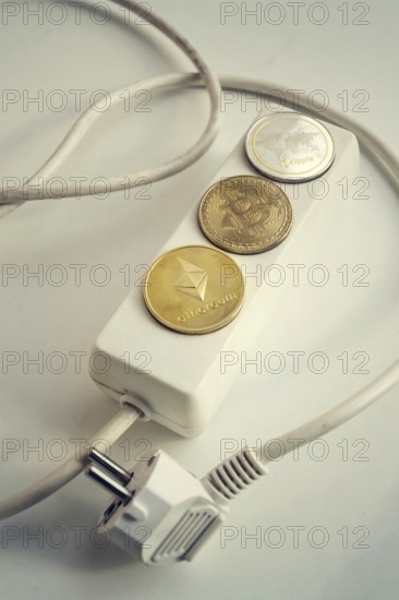Bitcoin, Ethereum and Ripple coins lying on power strip extension cord with 3 sockets, largest cryptocurrencies by market capitalization, cryptocurrency investing, energy consumption and footprint concept Prague Czech republic