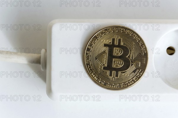 Bitcoin coin lying on power strip extension cord with empty socket, cryptocurrency investing, energy consumption and footprint concept, isolated on white background Prague Czech republic
