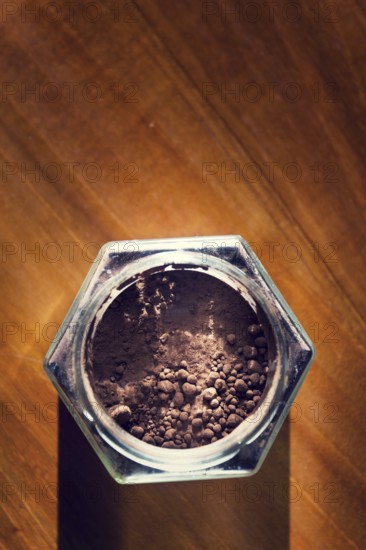 Cocoa powder in glass jar lying on wooden brown table, flat lay view, healthy diet Prague Czech republic
