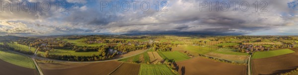 The picture shows a picturesque landscape with rolling hills, fields and forests during a colorful sunset. The clouds split and offer a clear view of nature. Bogen, Lower Bavaria
