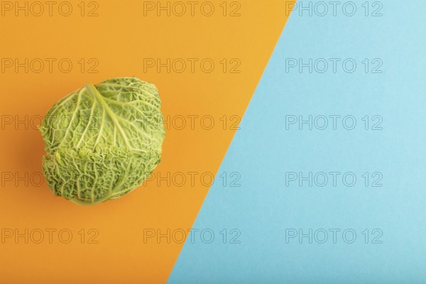 Green lettuce on blue and orange pastel paper background. Top view, copy space, flat lay. healthy food, vegetable, minimalism