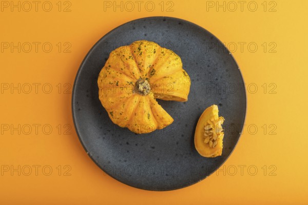 Orange Pumpkin on blue plate on orange pastel paper background. Top view, copy space, flat lay. healthy food, vegetable, minimalism, contrast