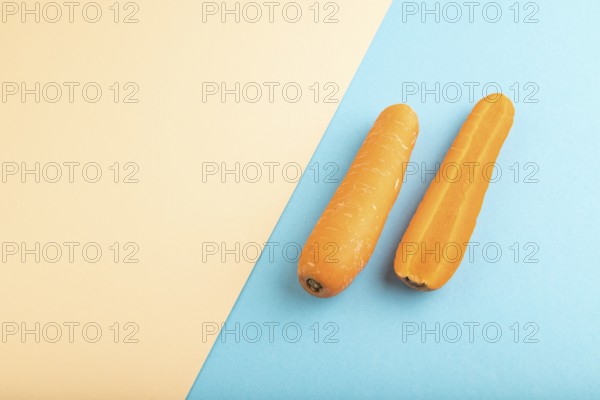 Orange Carrot on orange and blue pastel paper background. Side view, copy space, flat lay. healthy food, vegetable, minimalism