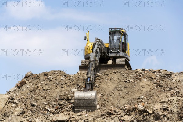 Yellow construction digger, excavator on demolition site stand on debris, sunny day clear blue sky, Prague, Czech republi
