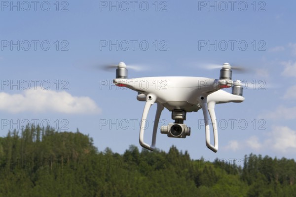 White drone quadrocopter with camera flying over forest Pisek Czech republic