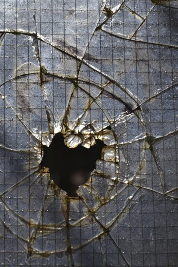 Hole in broken shattered security glass, insurance, security, vandalism or crime concept