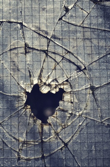 Filtered vintage photograph of hole in a broken security glass