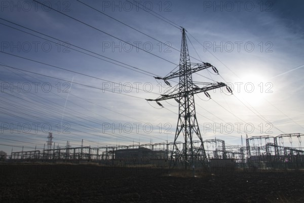 Electricity pylon from distribution power station with sun in background Prague Czech republic