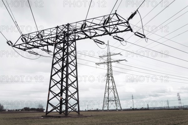 Electricity pylons conducting current from distribution power station, solar renewable energy and grid stability concept, copy space dramatic clouds Prague Czech republic