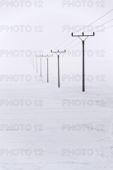 Electricity pylons from distribution power station disappearing in deep fog, winter freezing weather concept Prague Czech republic