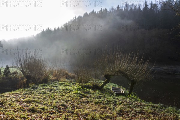 Boat under willow trees in foggy morning, shore of Luznice River, Czech Republic, peaceful relaxation leisure free time or weather forecast concept Krivoklat Czech republic