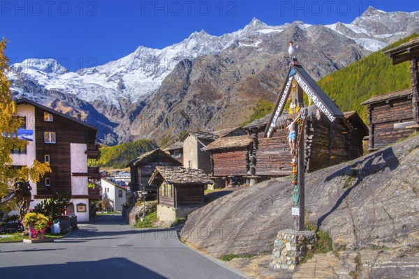 Saas wayside shrine with typical granaries on the outskirts of the village with Alphubel 4206m and Mischabel group 4545m in autumn, Saas-Fee, Saasertal, Valais, Switzerland